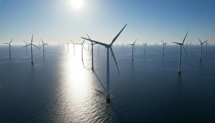 Морская ветровая электростанция с рядами турбин, уходящими к горизонту. Вид с воздуха на спокойное море в солнечный день.